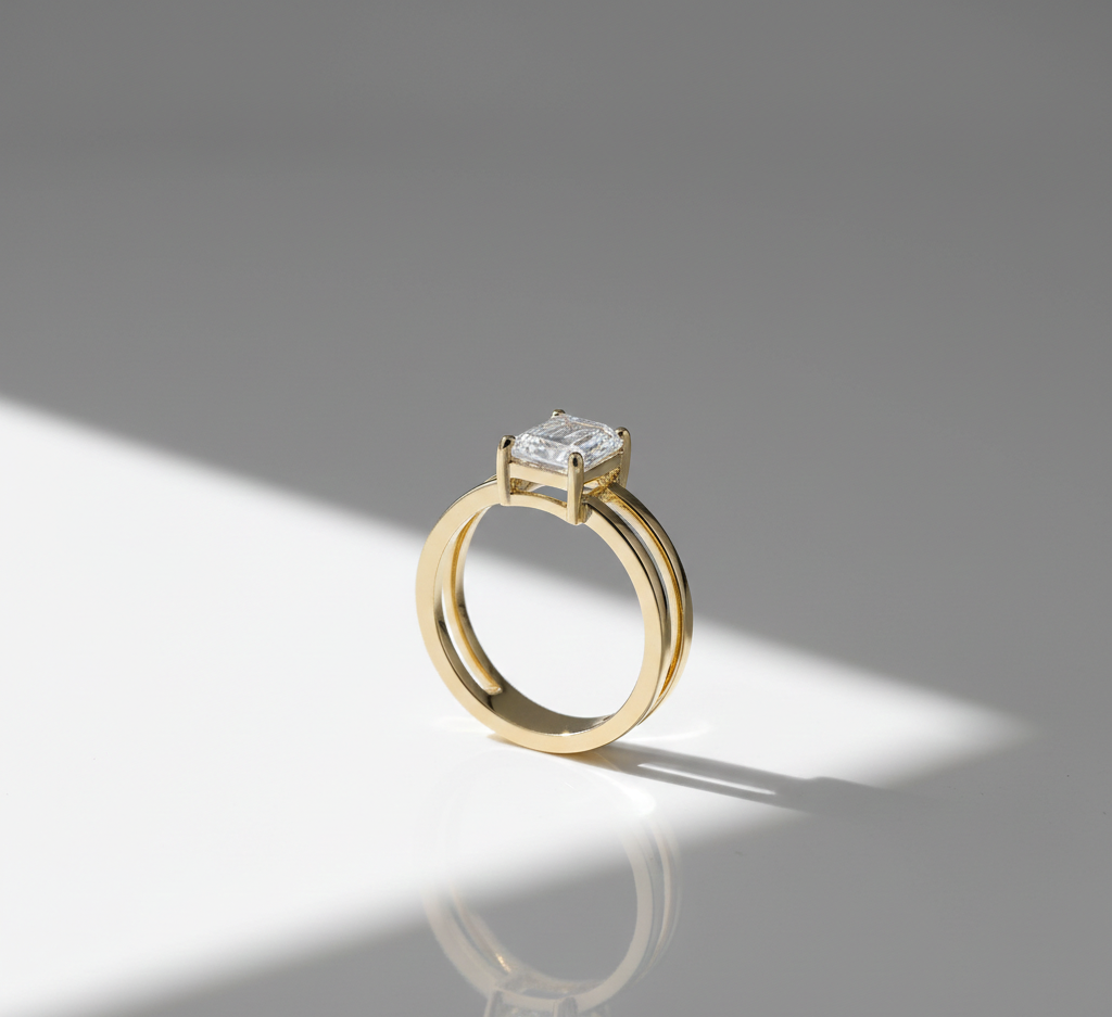A gold ring with a large diamond solitaire setting against a background divided between white and gray.