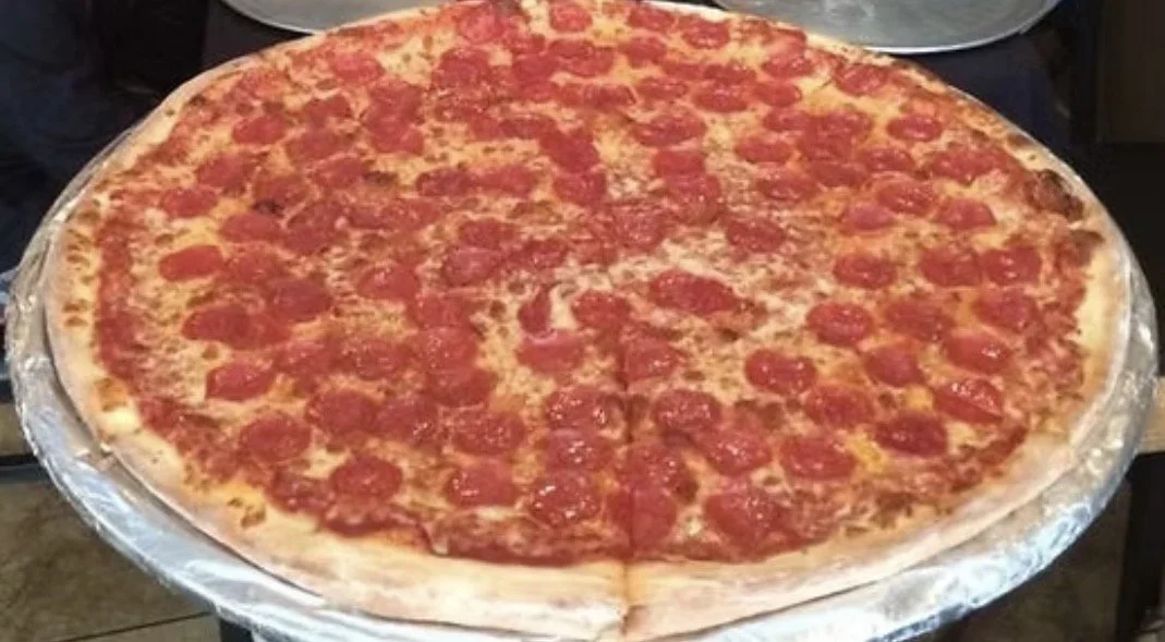Large pepperoni pizza with melted cheese on a silver tray.