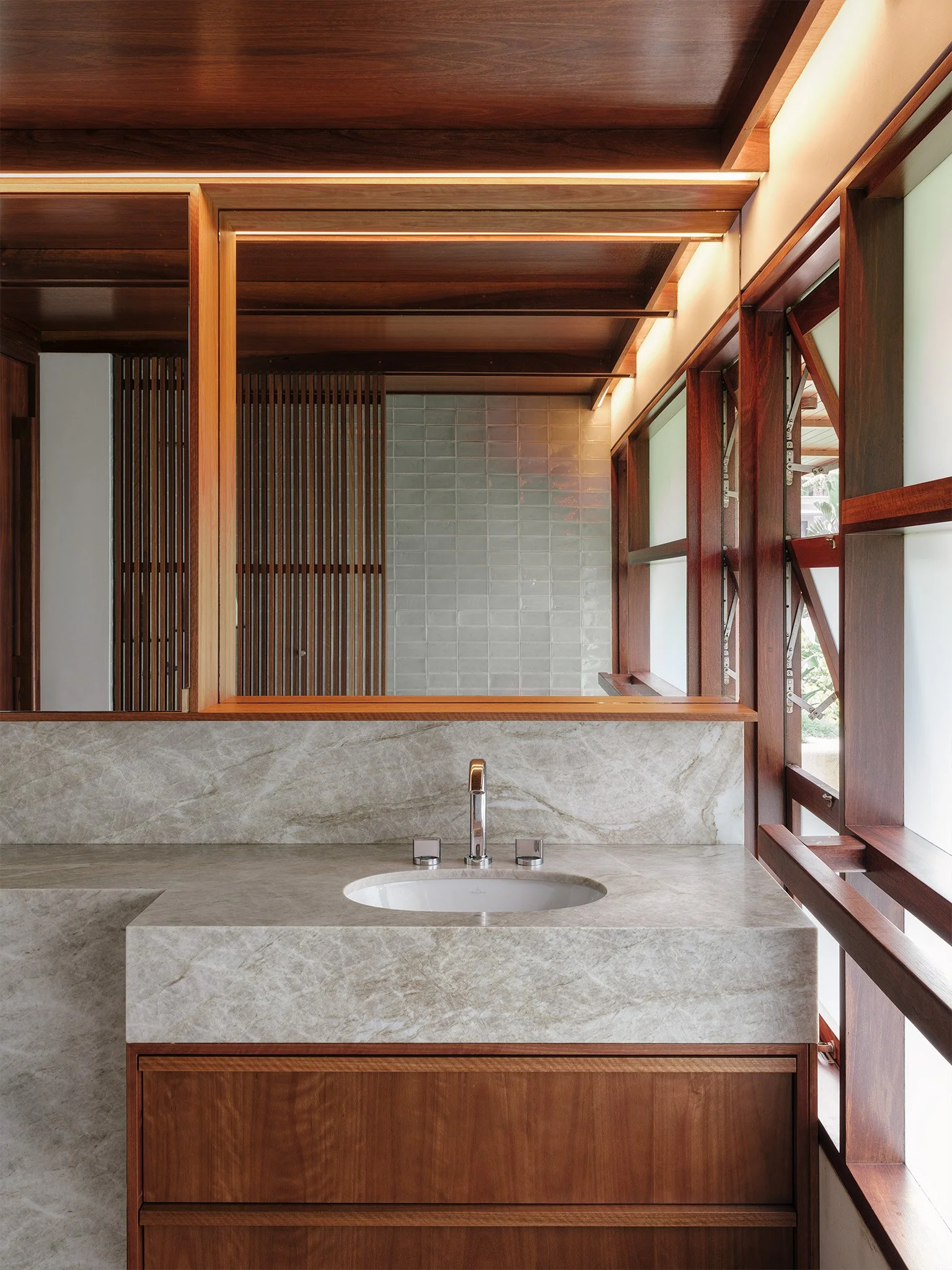 Modern bathroom with strip lighting and stone vanity.