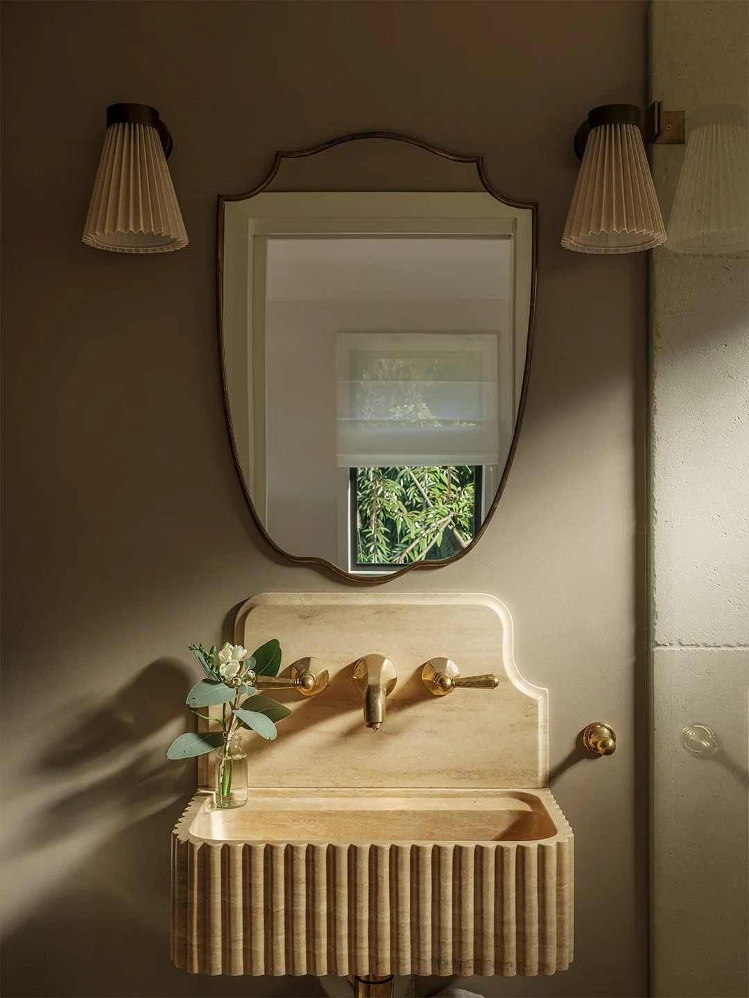 Designer bathroom with brass fittings and natural light.