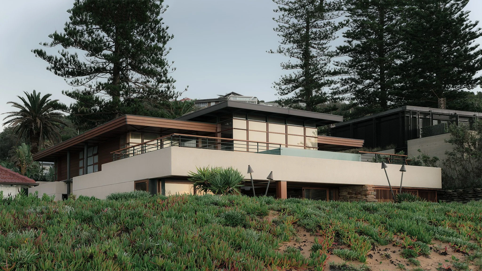 Modern beach house with stone exterior walls and a second-floor swimming pool overlooking the ocean.
