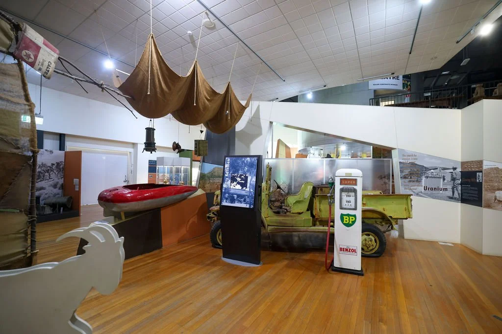 Isa Experience Museum exhibit featuring an old military vehicle, a red canoe, a green tent, and various informational displays.