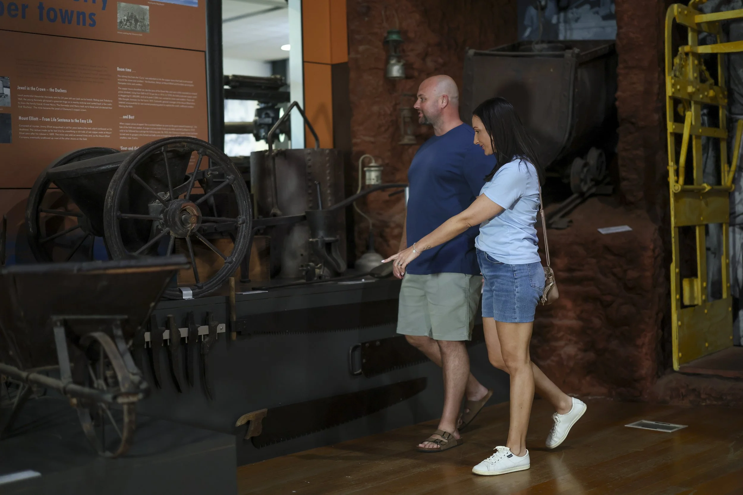 A man and a woman visiting the Isa Experience museum exhibit of historical machinery, standing side by side and observing an old machine on display.