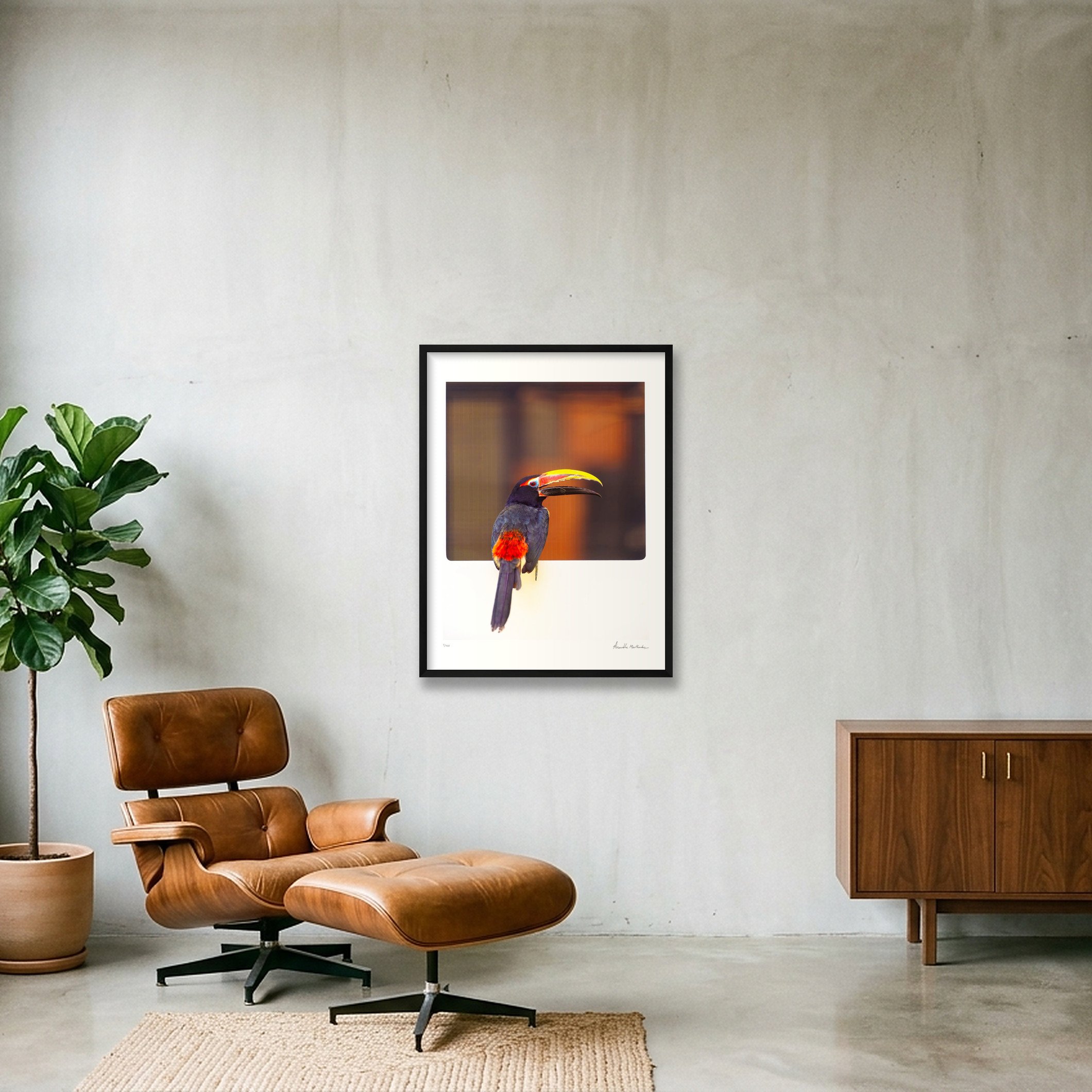 Living room with a brown leather chair and puff, a large potted plant on the left, a framed toucan picture on the wall, a wooden side table, and a beige rug.