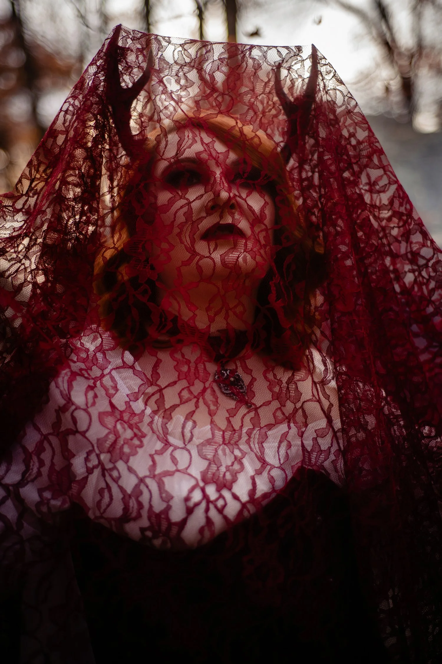 Woman with red hair with stag horns wearing crimson makeup