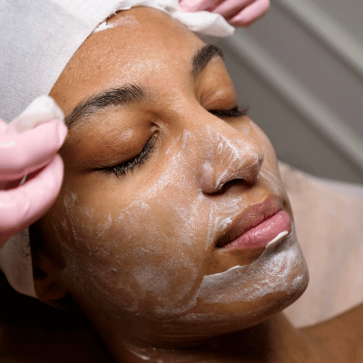 Close-up of a woman receiving a facial treatment with white cream on her face.