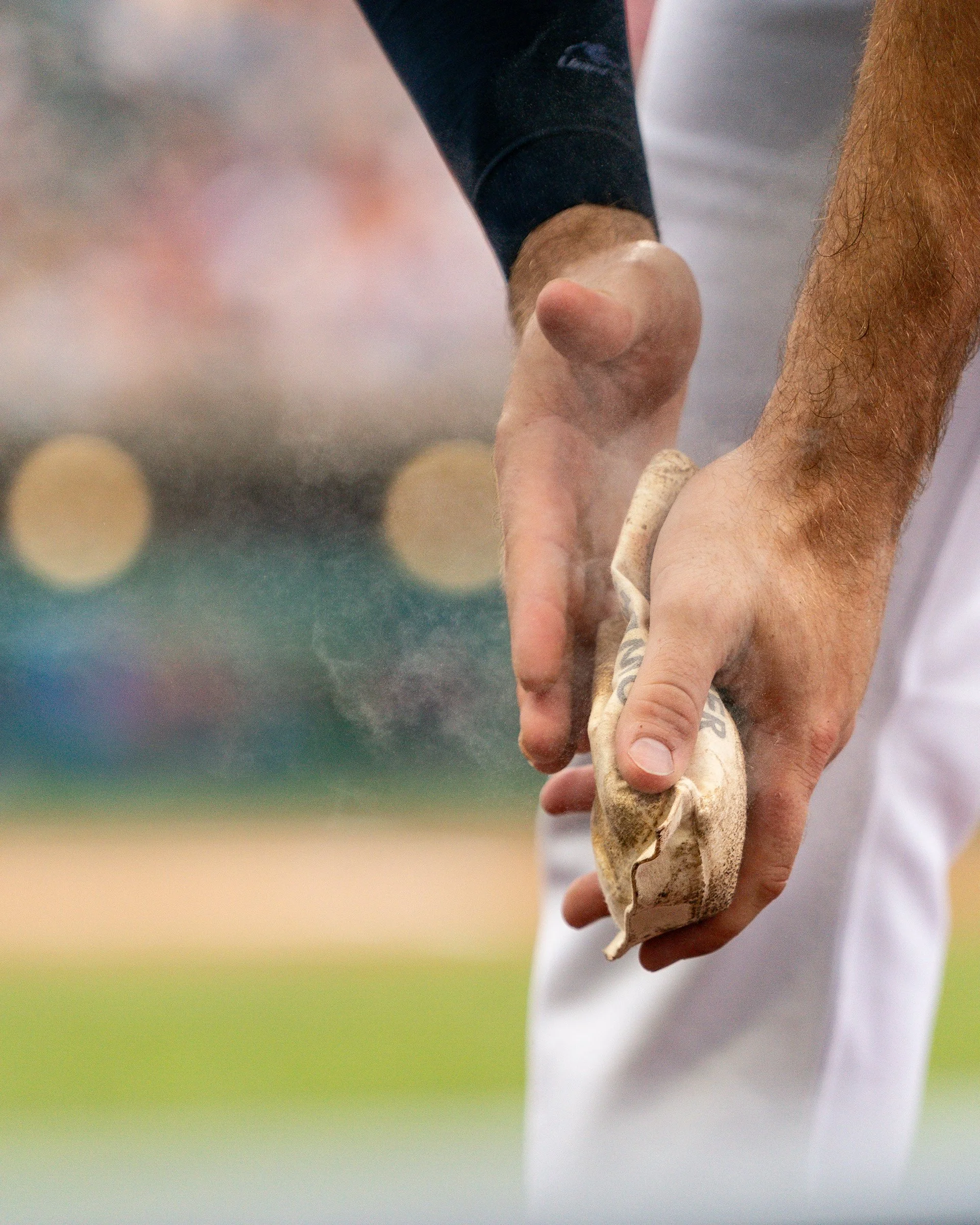 Close-up of a person's hand holding a piece of wood or possibly a shoe, with a blurred outdoor background.