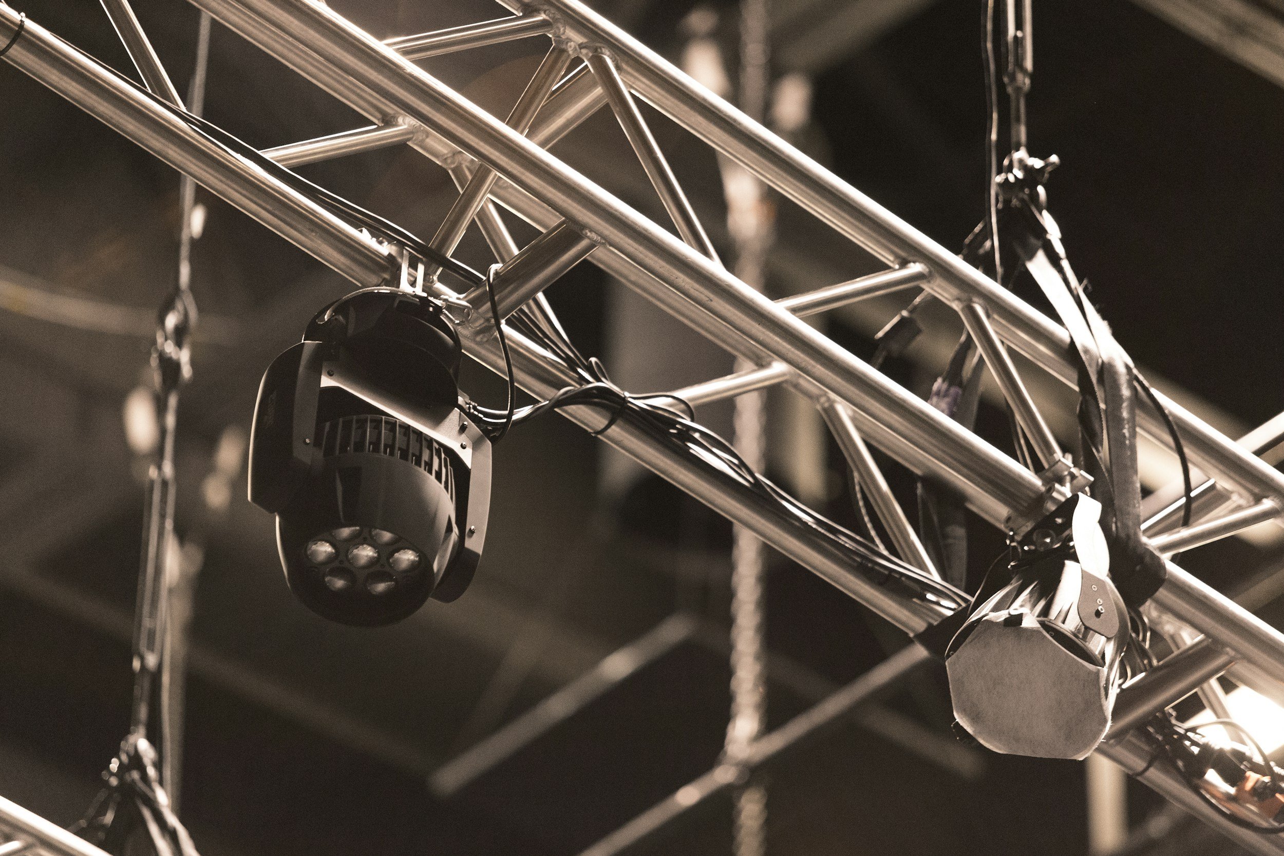 Close-up of a metallic rigging structure with a black stage light or spotlight hanging from it.