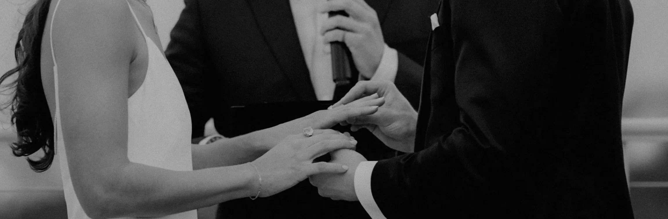 A couple getting married during a wedding ceremony, with a person officiating and holding a microphone.