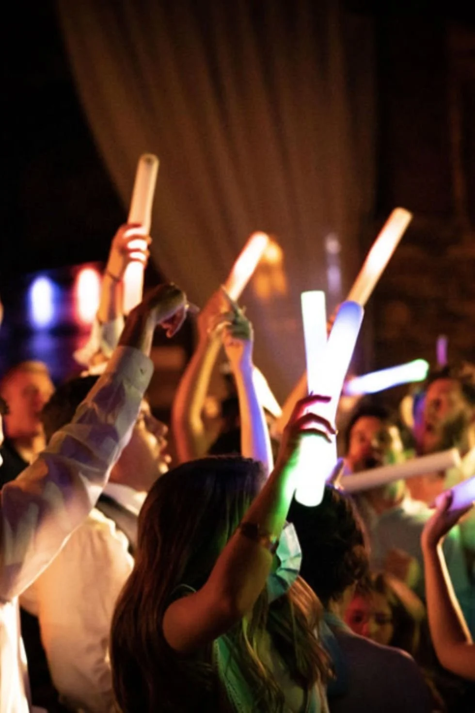 Crowd at a concert or event holding illuminated glow sticks.