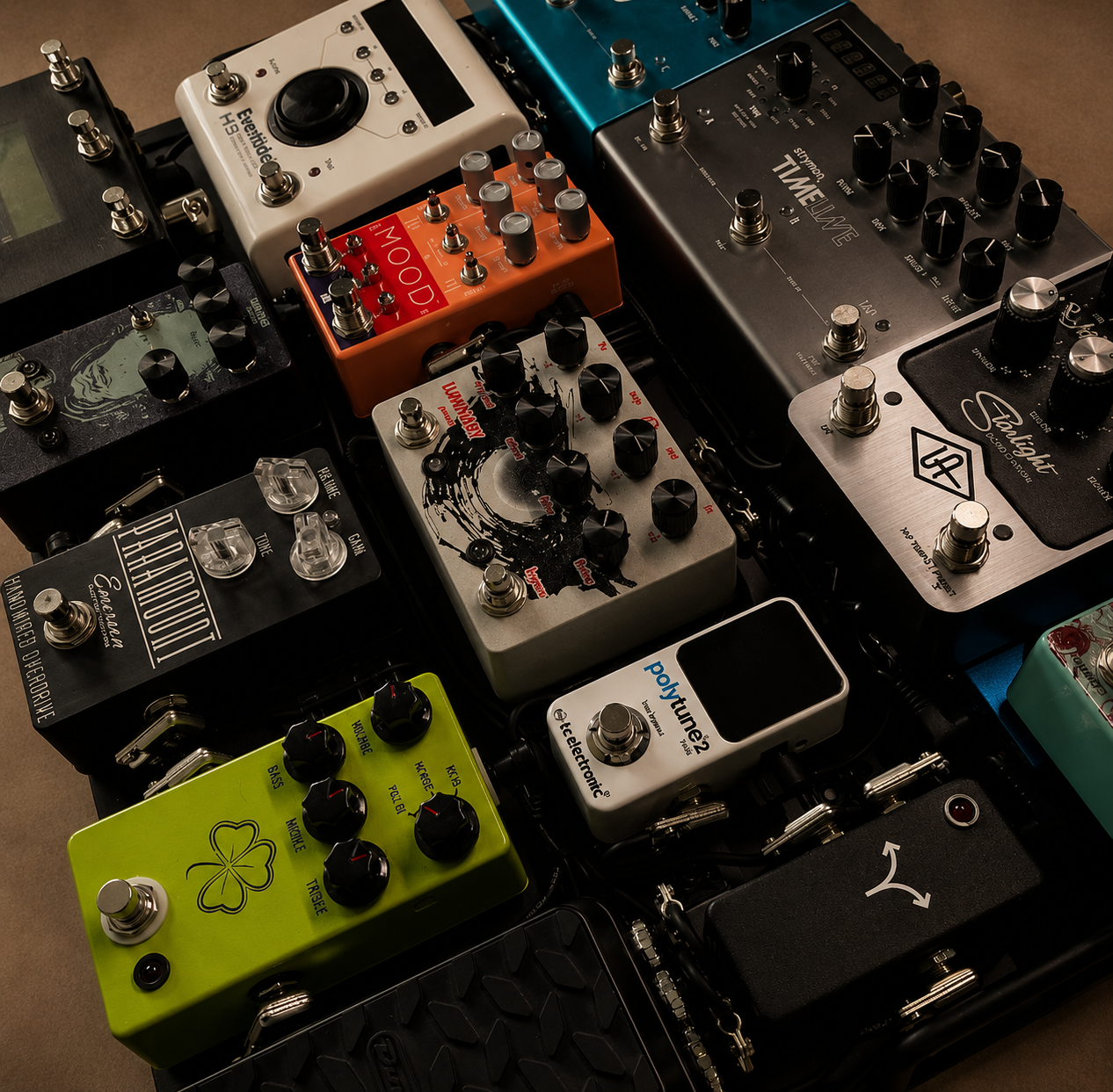 A collection of guitar effect pedals on a pedalboard, including brands like Strymon, Boss, and Telefunken, with various knobs and switches.