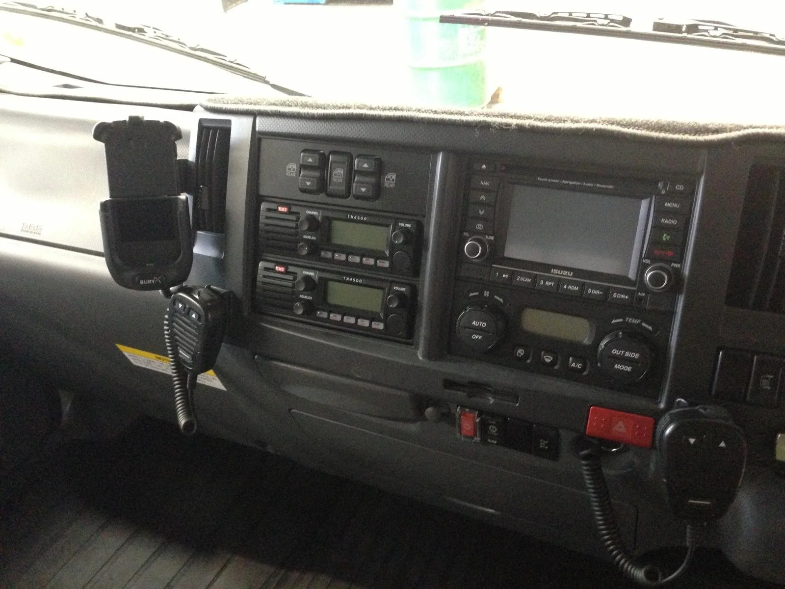 Dashboard of a vehicle with communication devices, vehicle controls, and a mounted phone holder.