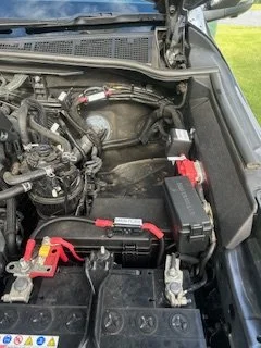 Car engine with battery and wiring visible under the hood.