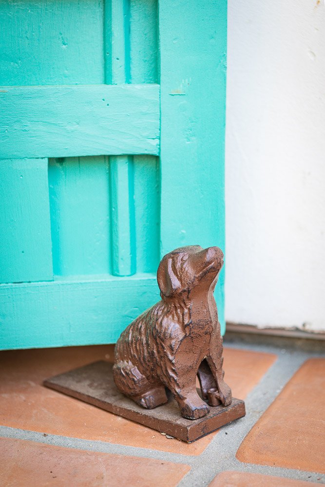 Bronze dog sculpture beside a turquoise front door