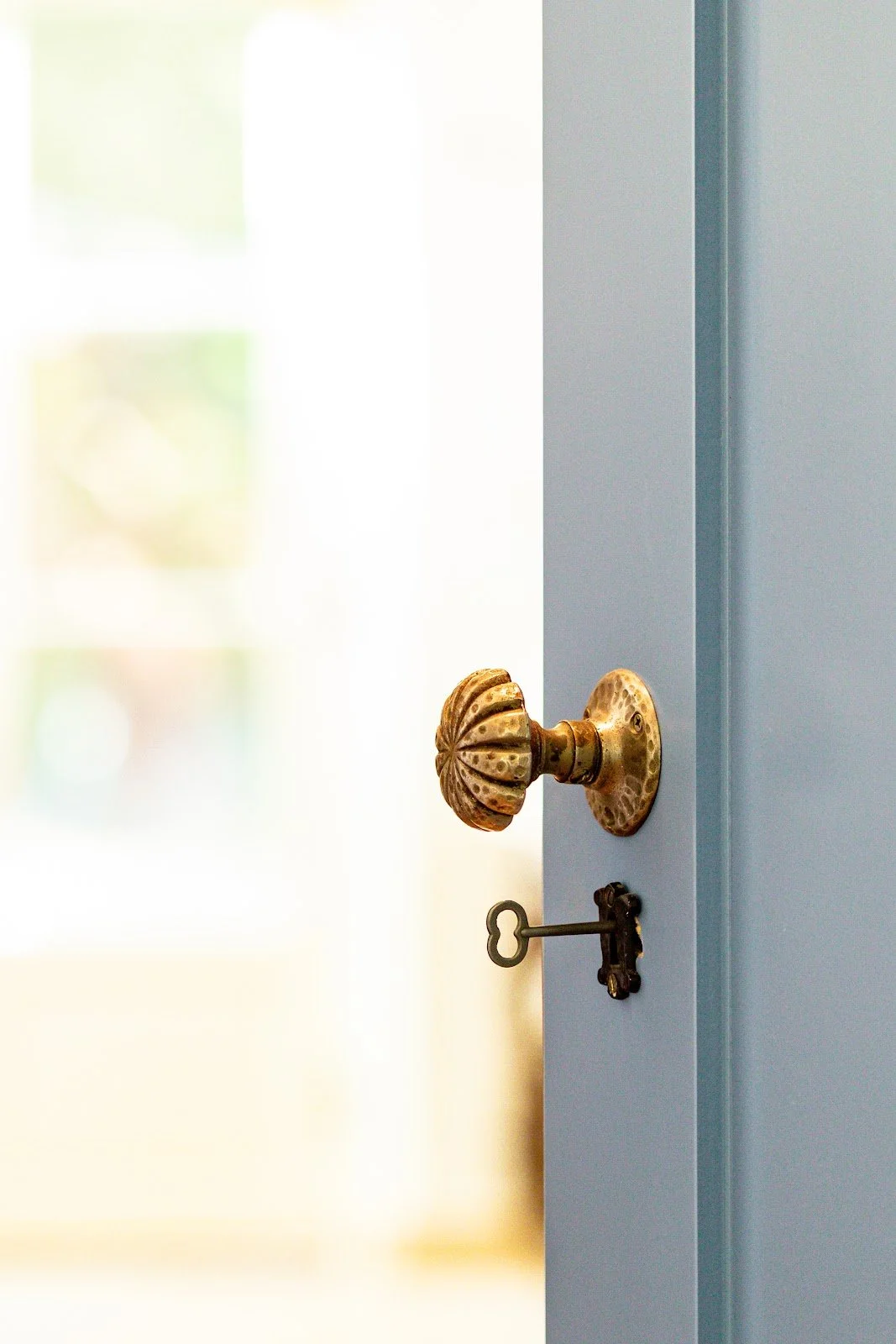 Antique brass door knob and key on a blue-gray door