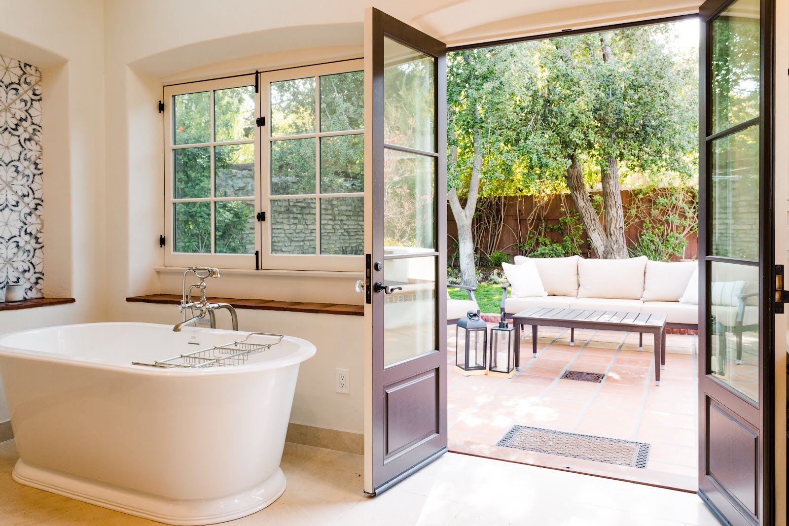 Freestanding bathtub beside open French doors leading to a garden patio