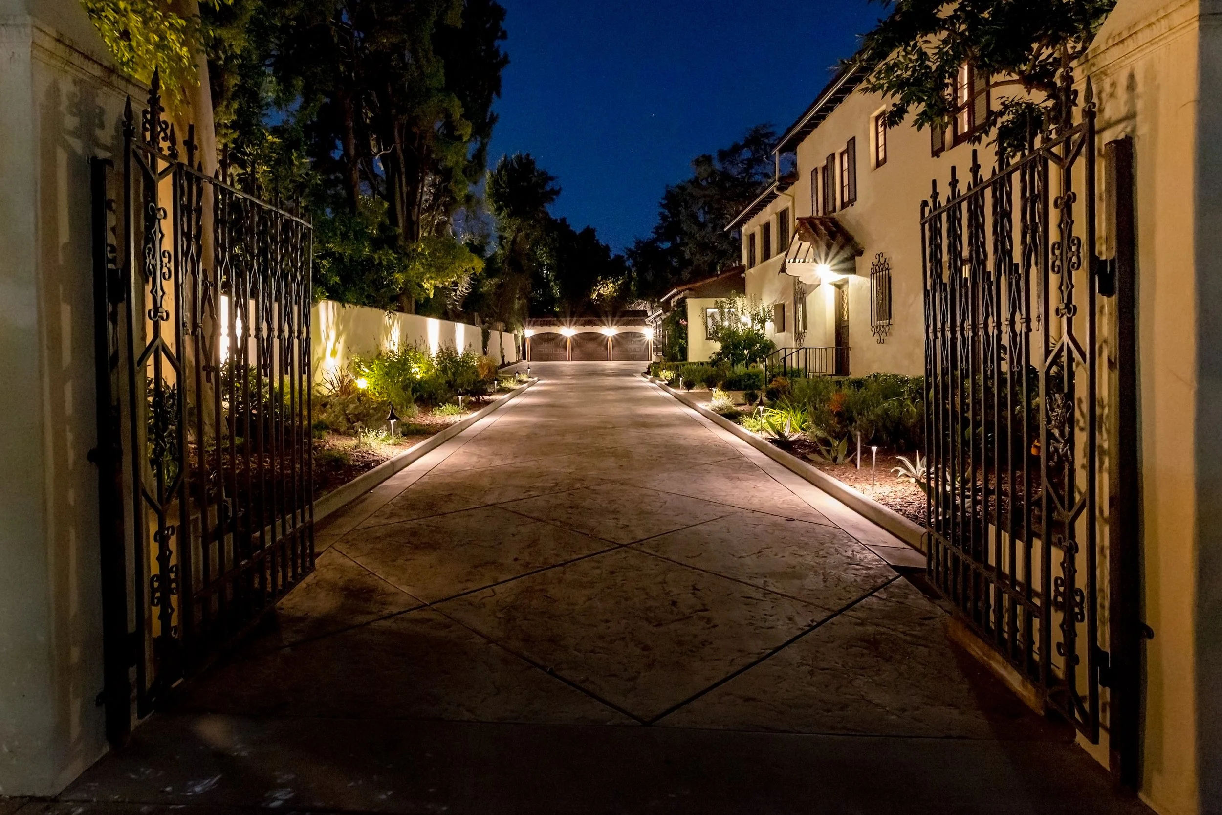 Landscaped driveway leading to the illuminated garage at night