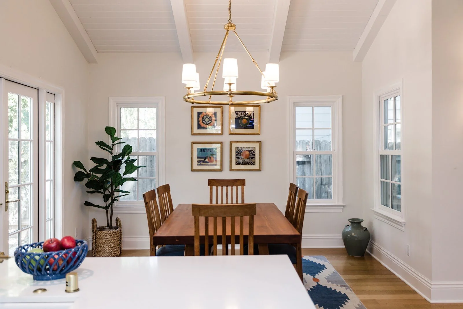 Bright dining room with a wood table, chandelier and framed artwork