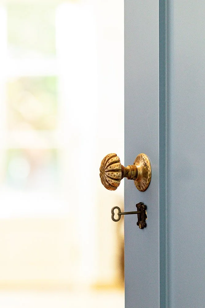 Antique brass doorknob and key on a blue painted door