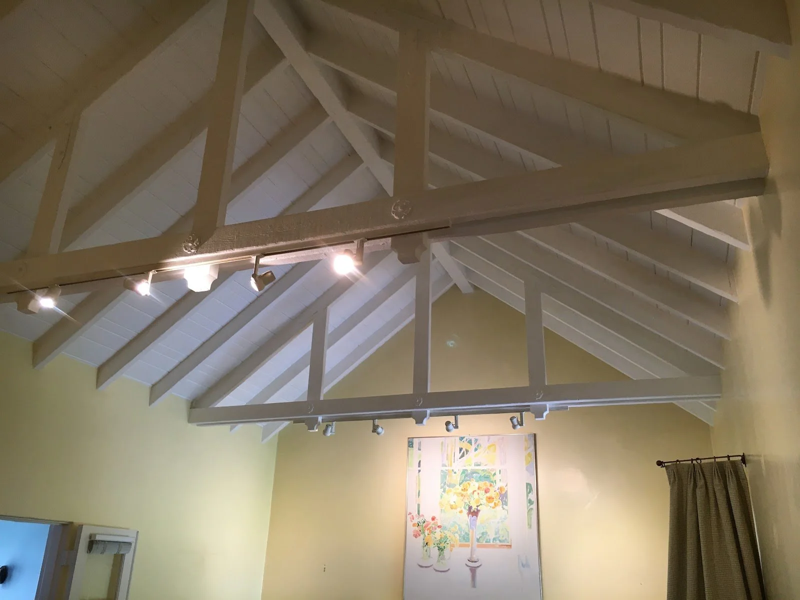 Vaulted living room ceiling with exposed beams and track lights before renovation