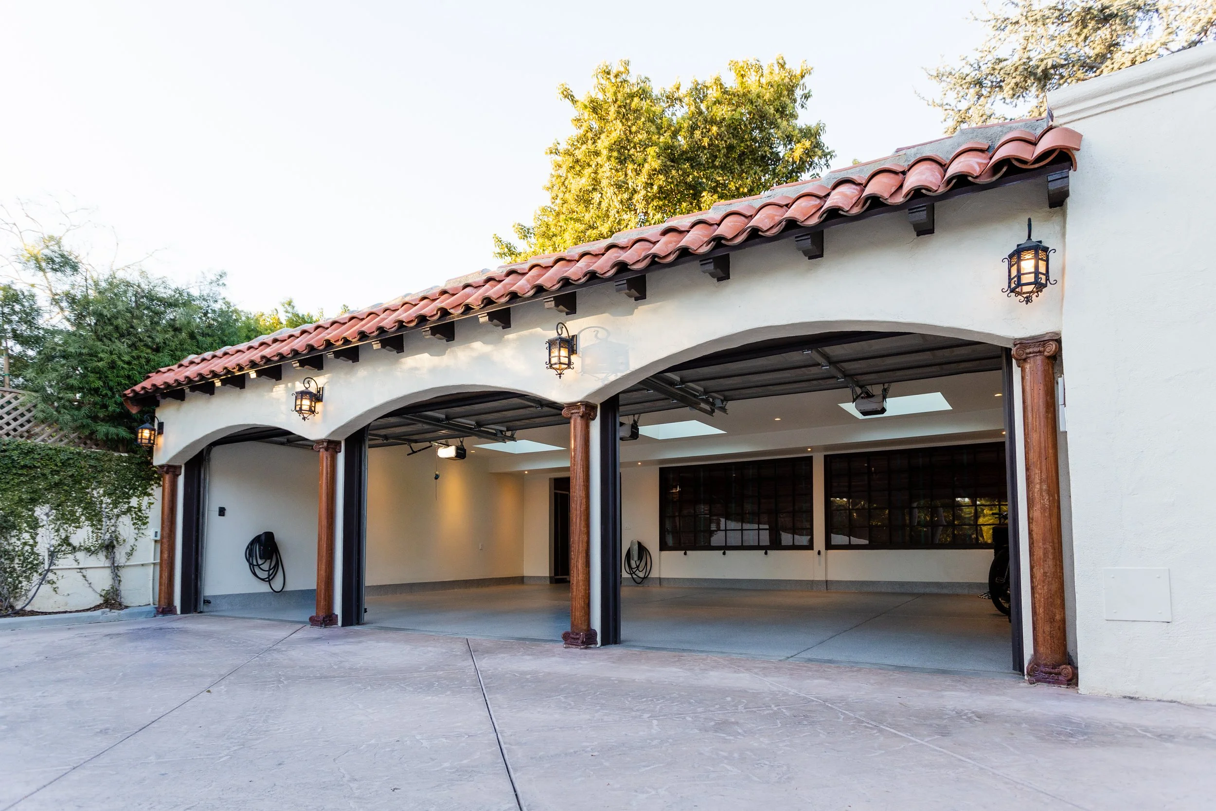 Three-car garage with arched openings, wood columns and red tile roof