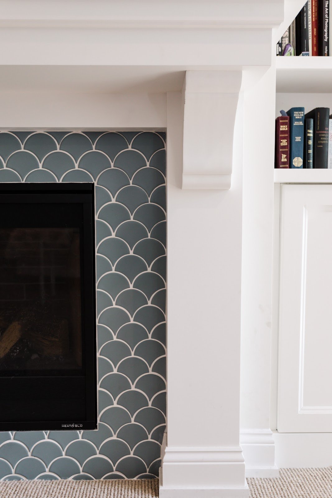 Black fireplace framed by blue scallop tile and white built-in shelves