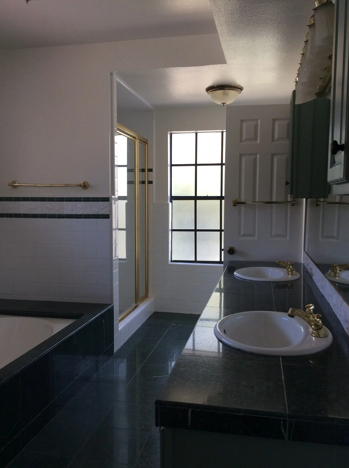 White and black tiled bathroom with a glass shower before renovation