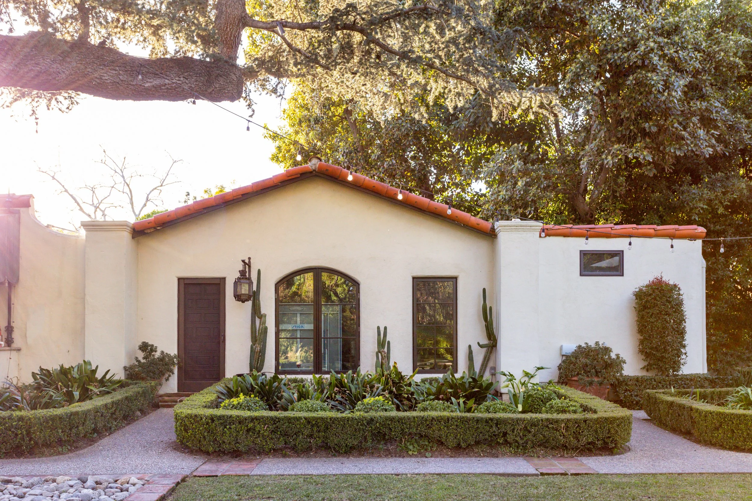 Spanish-style garden facade with an arched window and clipped hedges