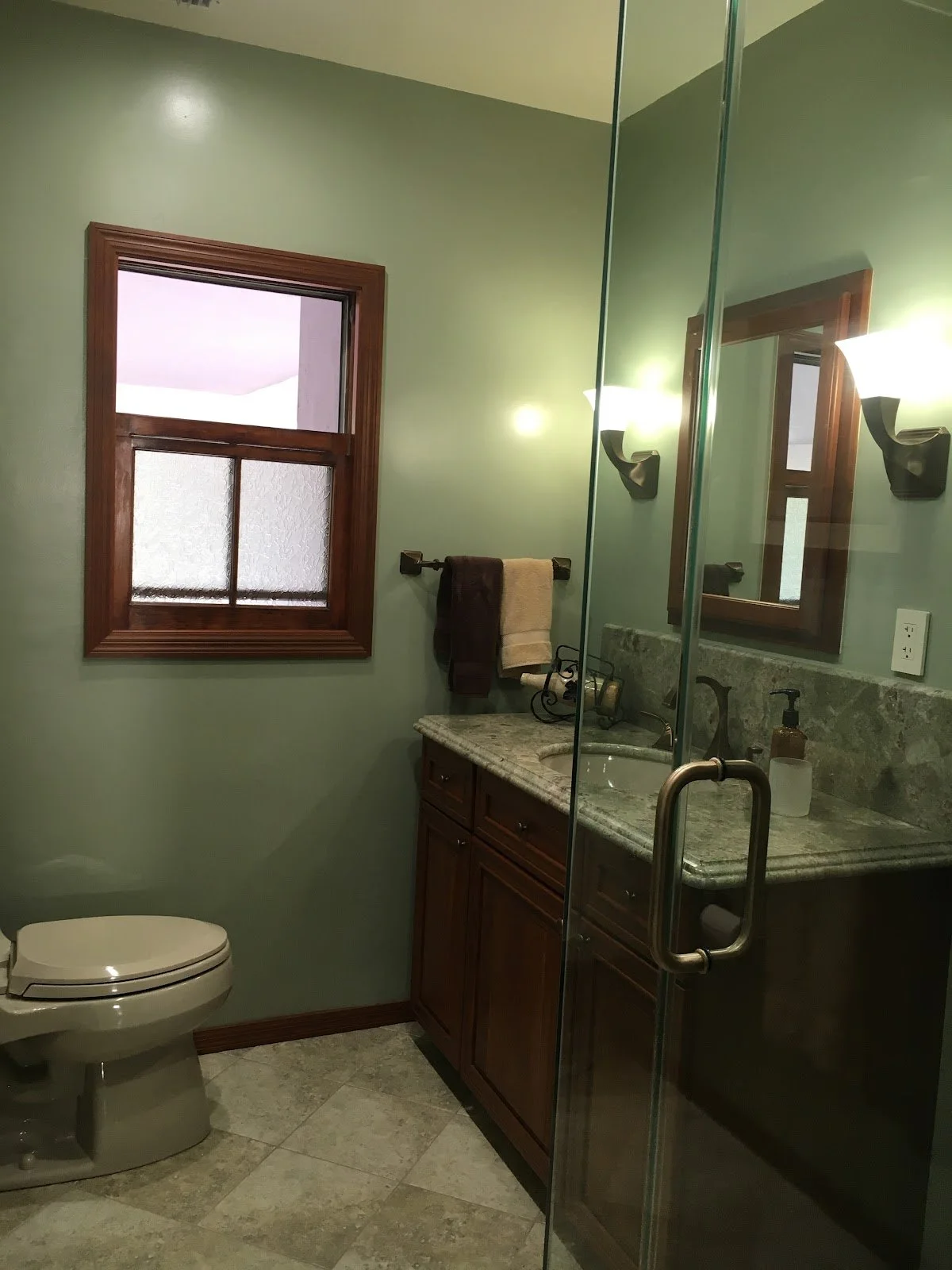 Green bathroom with dark wood vanity and glass shower before renovation