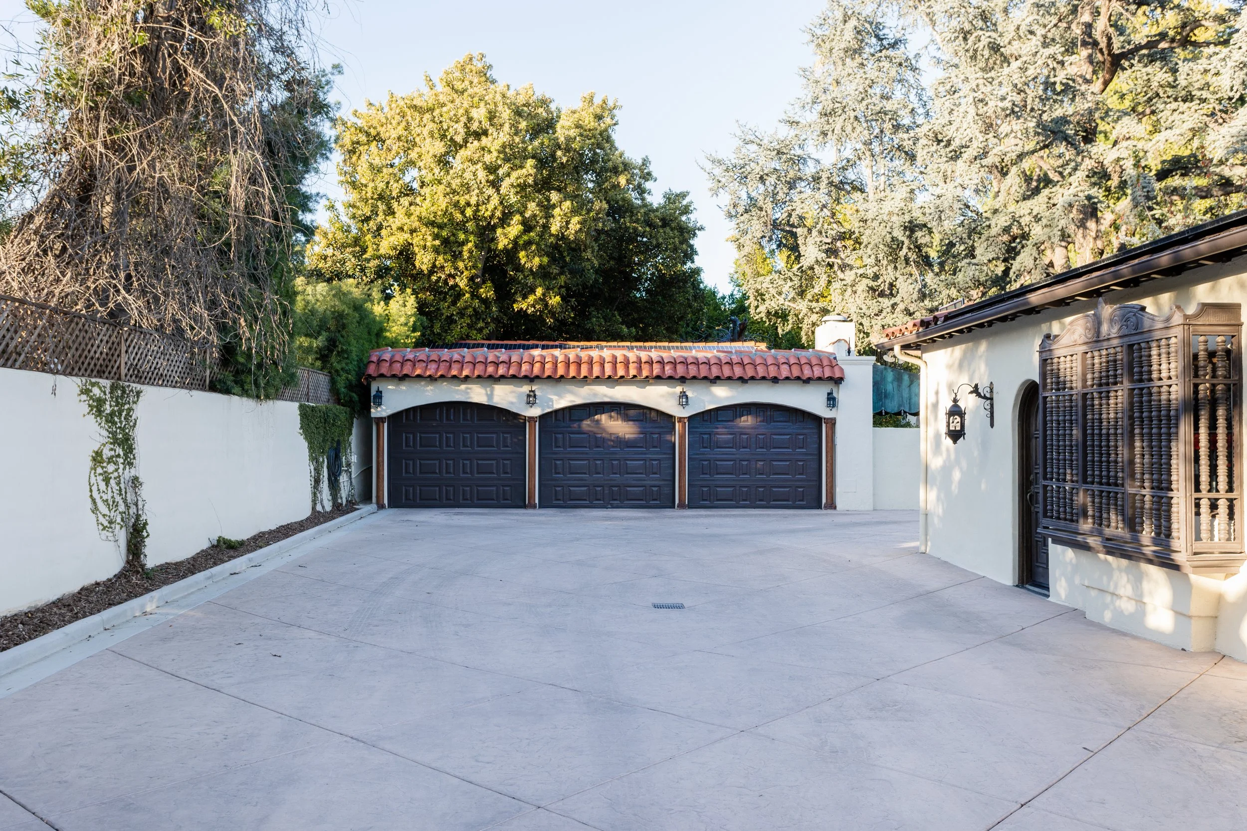 Three dark wood garage doors at the end of a broad driveway