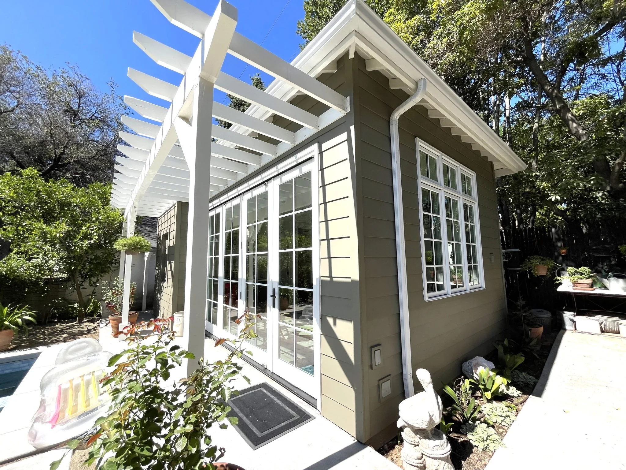 White pergola over French doors on a garden-facing home exterior