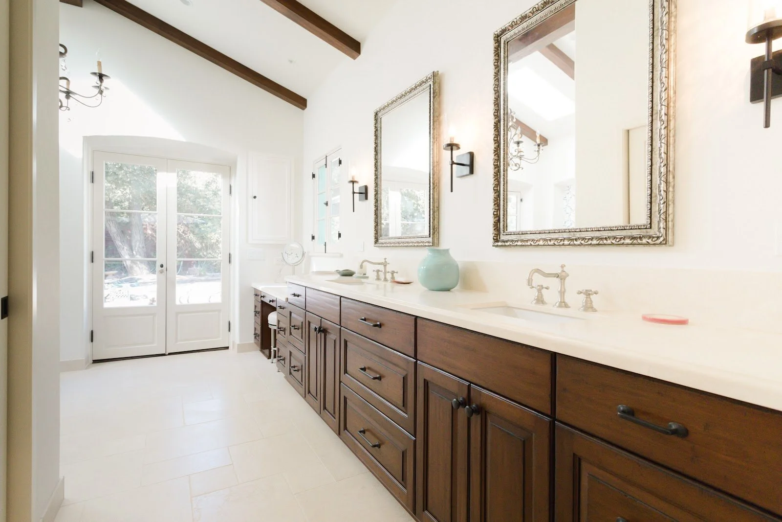 Bright bathroom with dark wood vanity, white countertop and framed mirrors