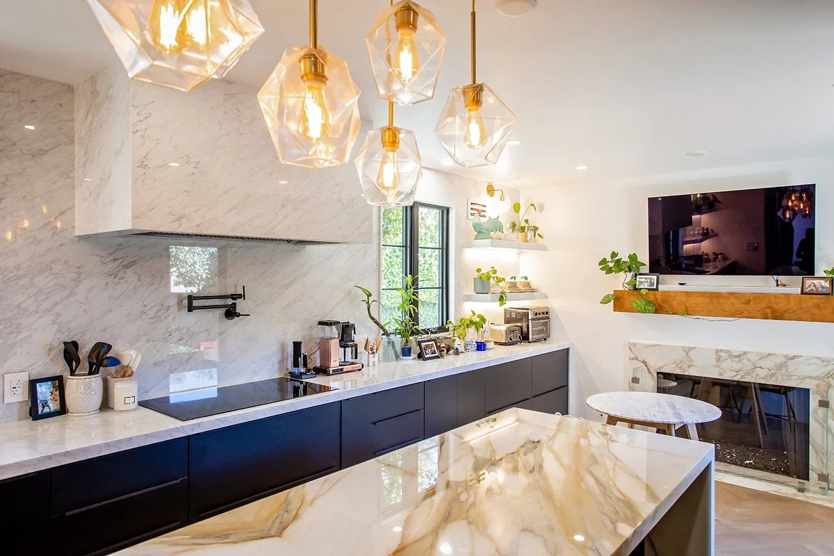 Kitchen with dark cabinets, marble backsplash and a waterfall-edge island