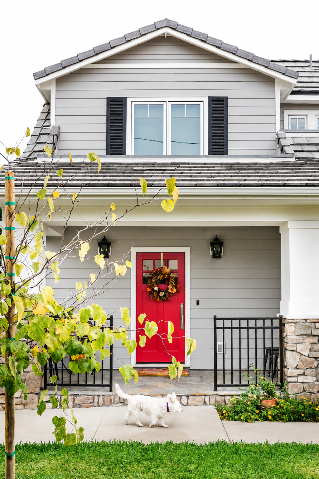 Gray Craftsman-style home with a red front door and black shutters