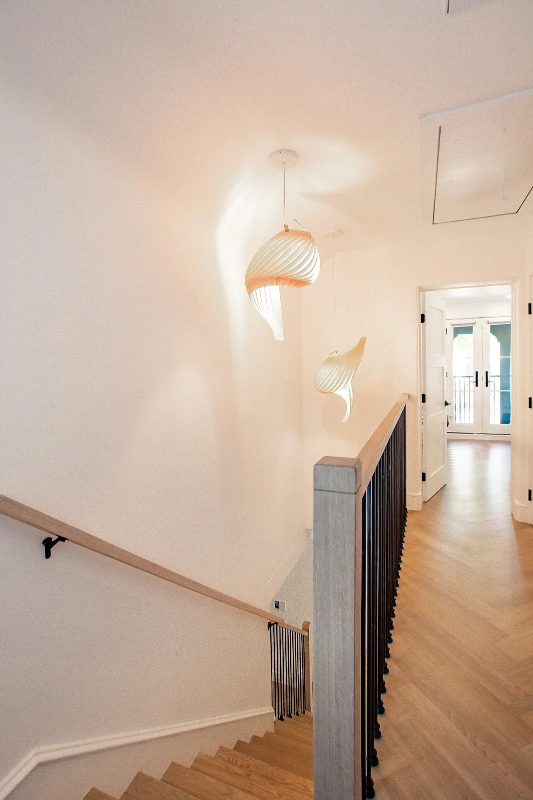 Wood staircase and hallway with sculptural pendant lights