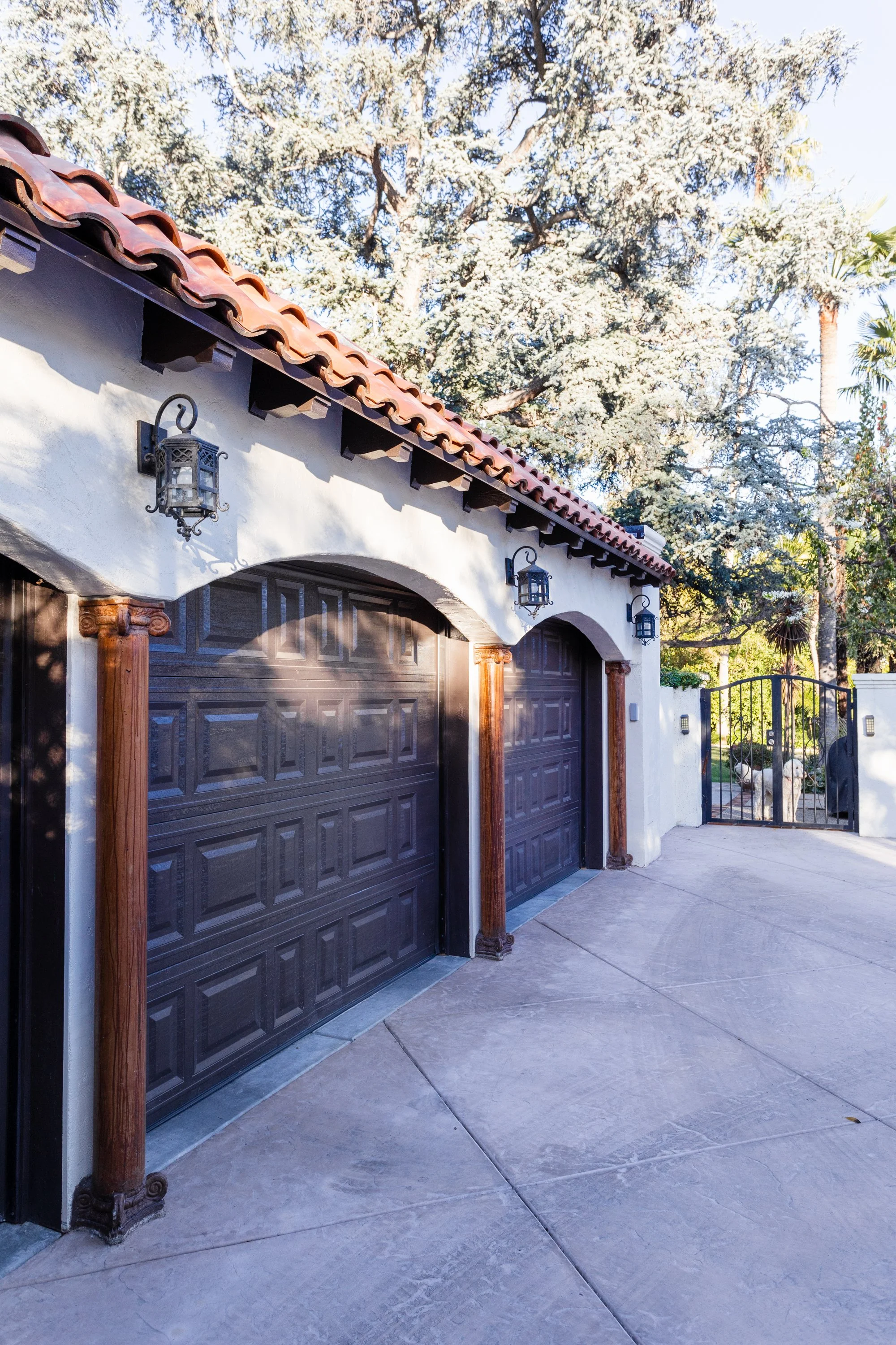 Dark wood garage doors framed by carved columns and arched stucco openings