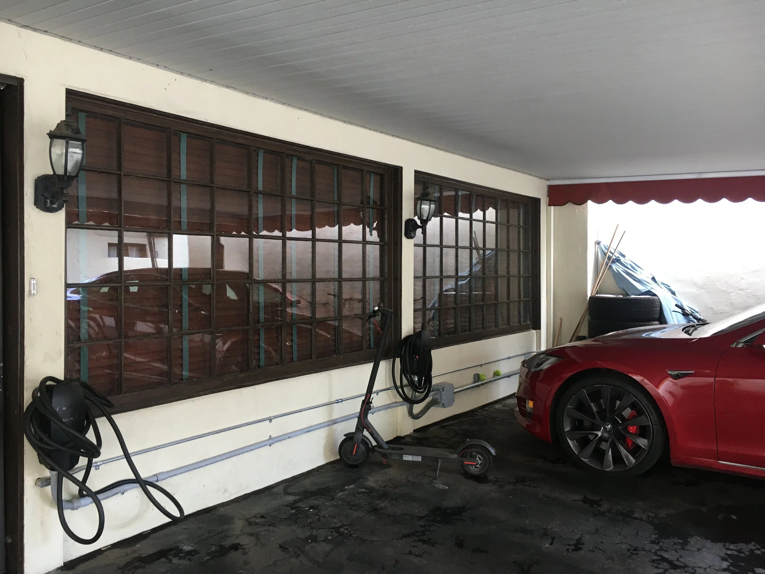 Covered carport with a parked car and equipment before renovation