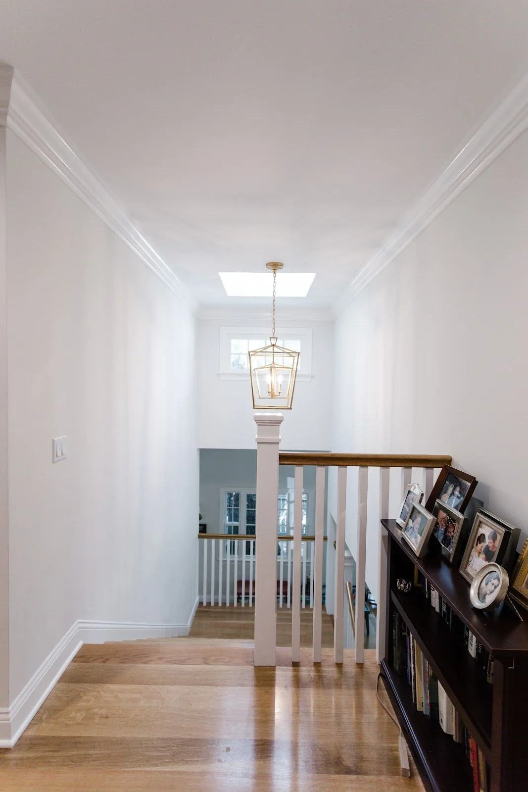 Bright entry hall with wood floors, white stair railing and a black console table