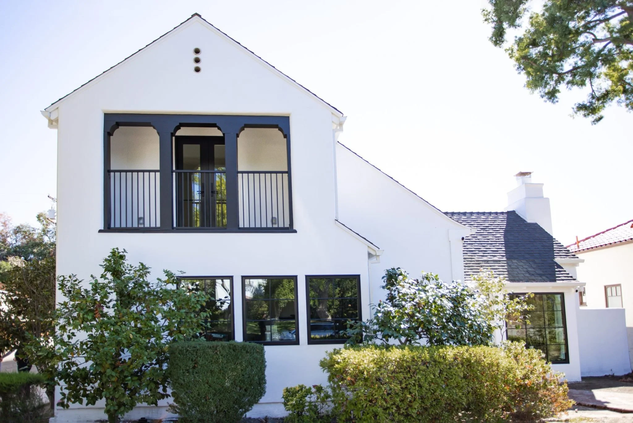 White Spanish-style home exterior with dark trim and balcony