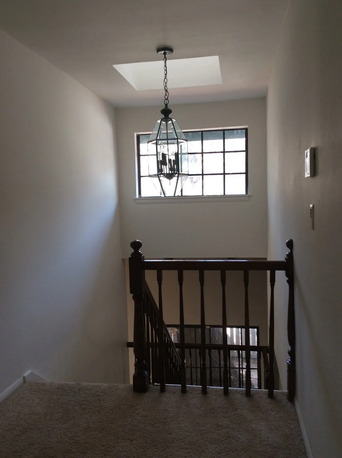 Dark wood staircase landing with a hanging lantern before renovation