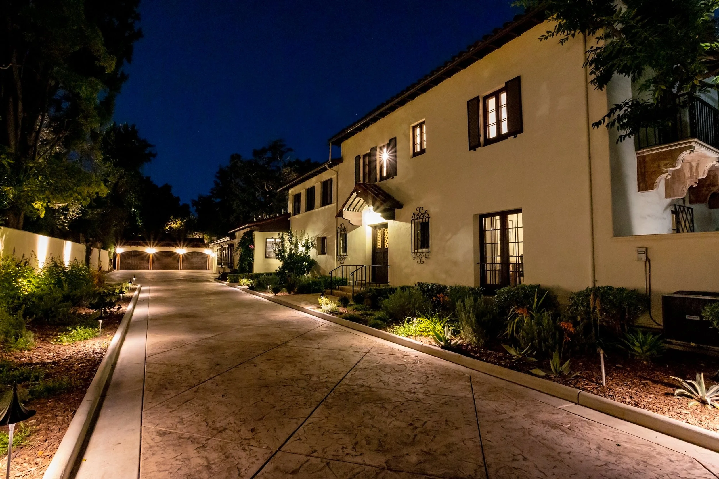 Illuminated Mediterranean-style residence and garage at night