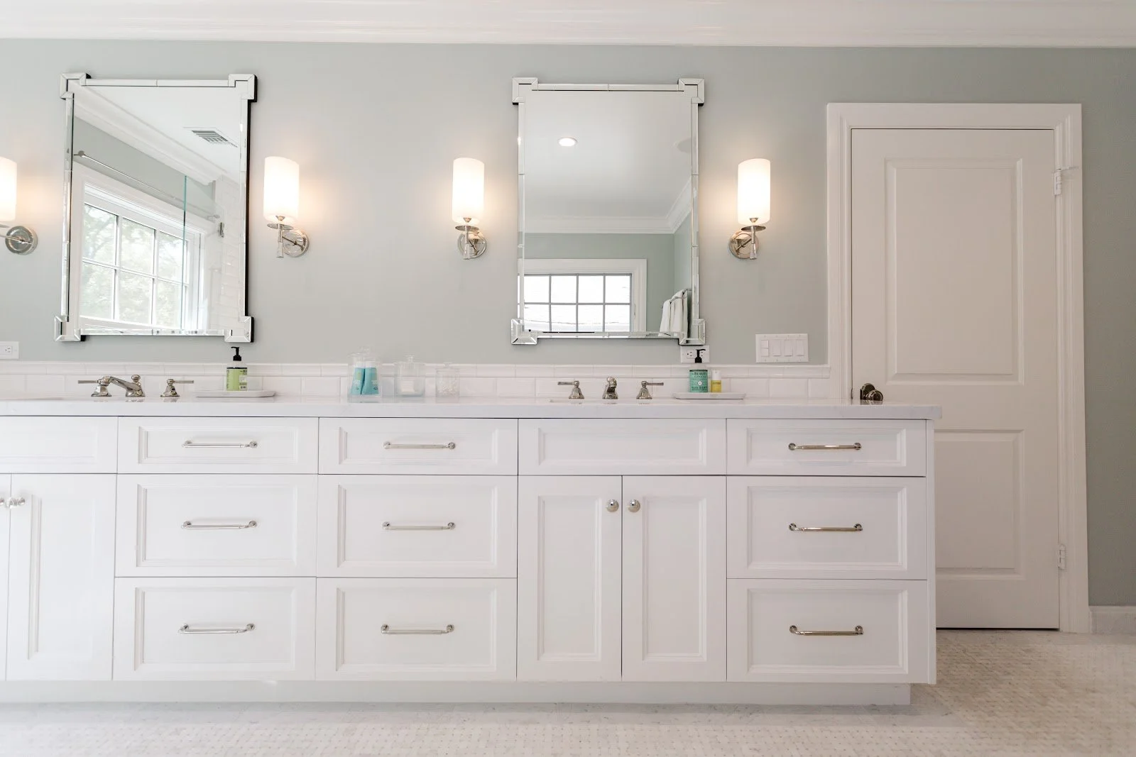 White bathroom vanity with paneled drawers, chrome fixtures and a framed mirror
