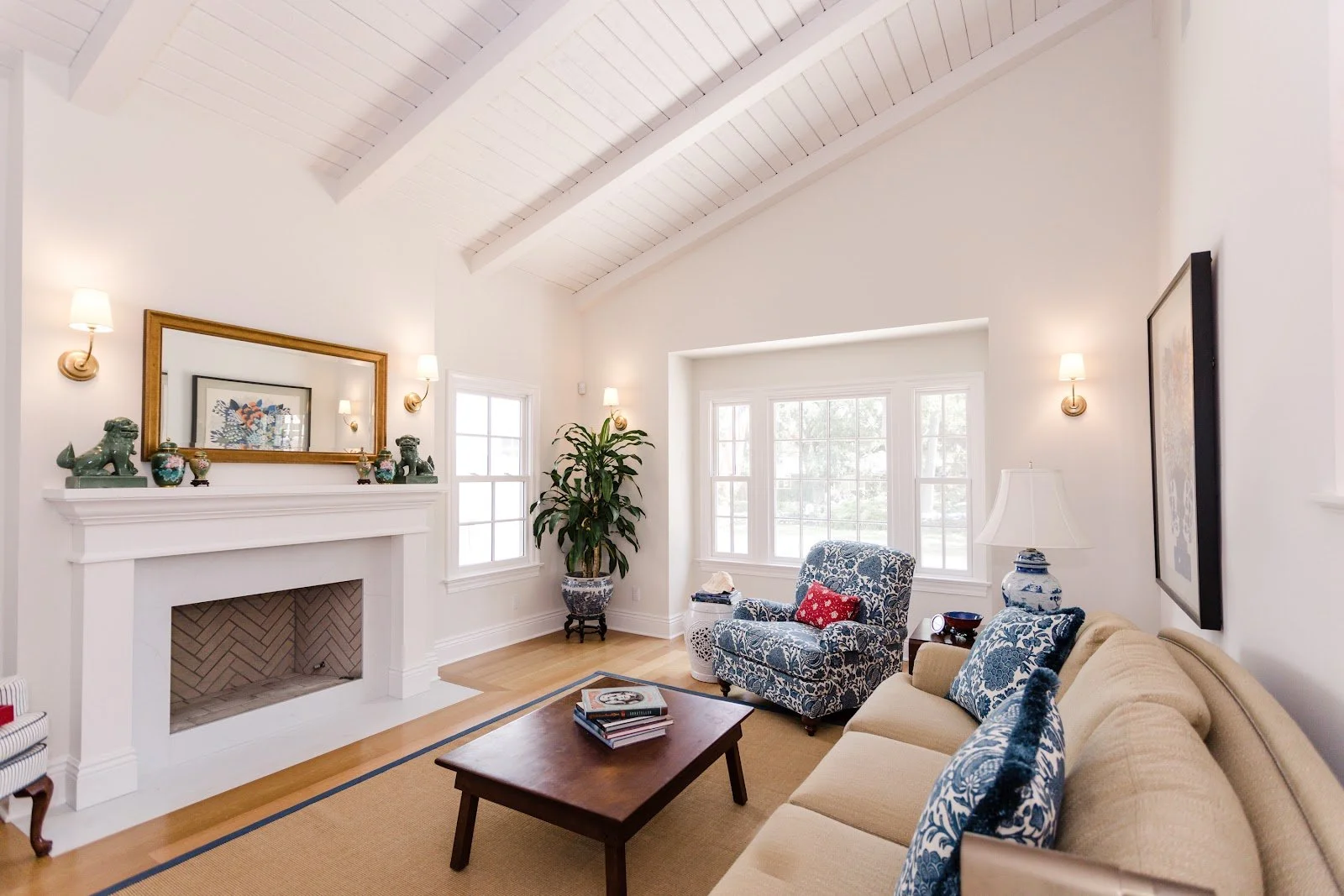 Bright living room with a vaulted white ceiling, fireplace and large windows
