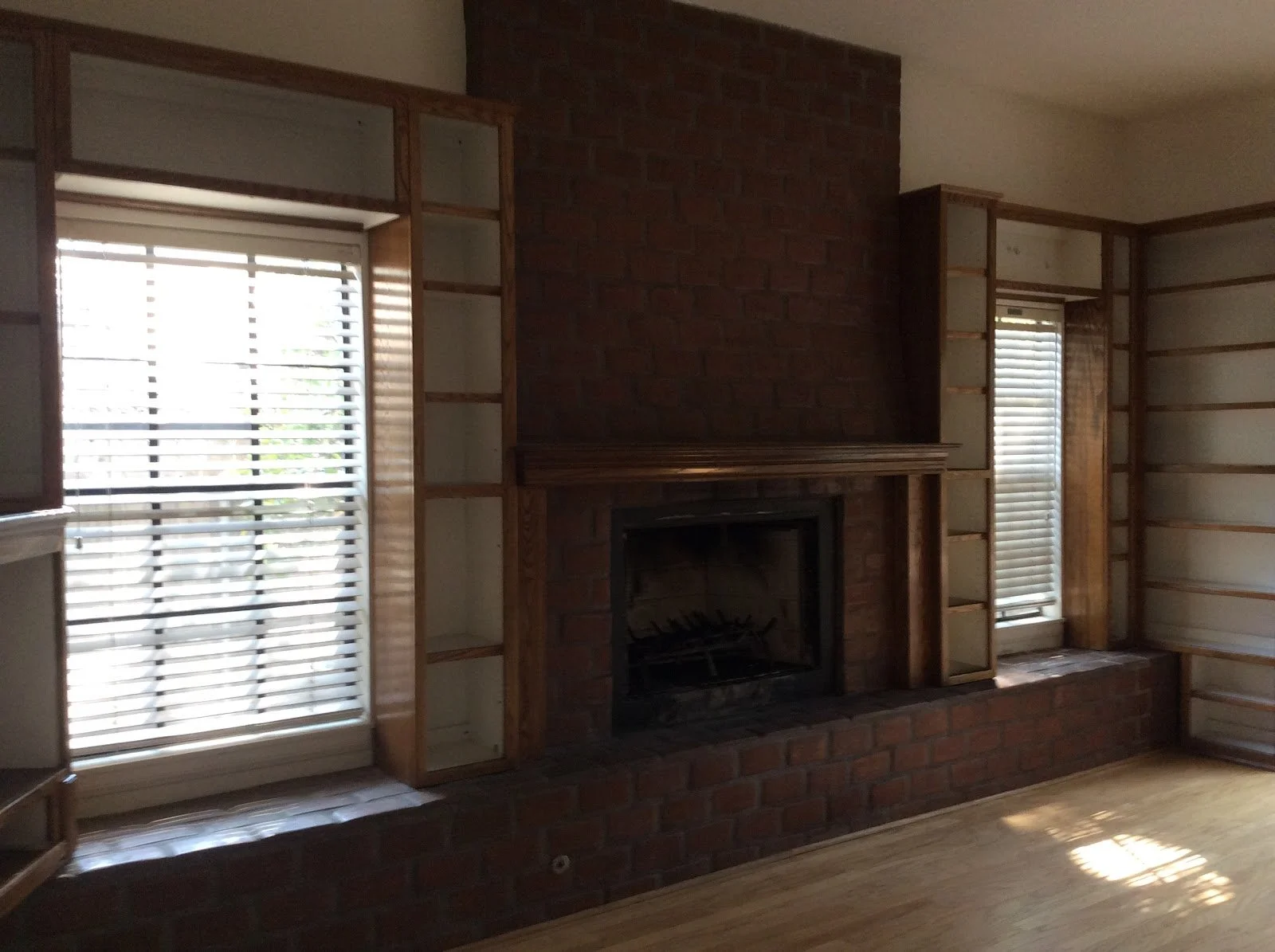 Brick fireplace and window with dark wood trim before renovation