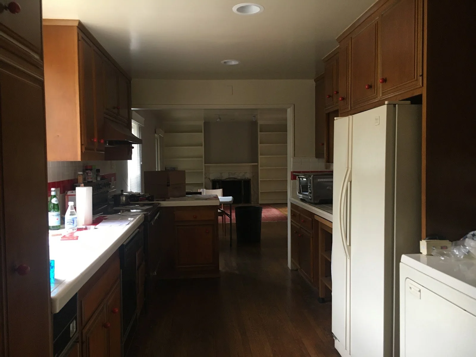 Narrow kitchen with dark wood cabinets before renovation