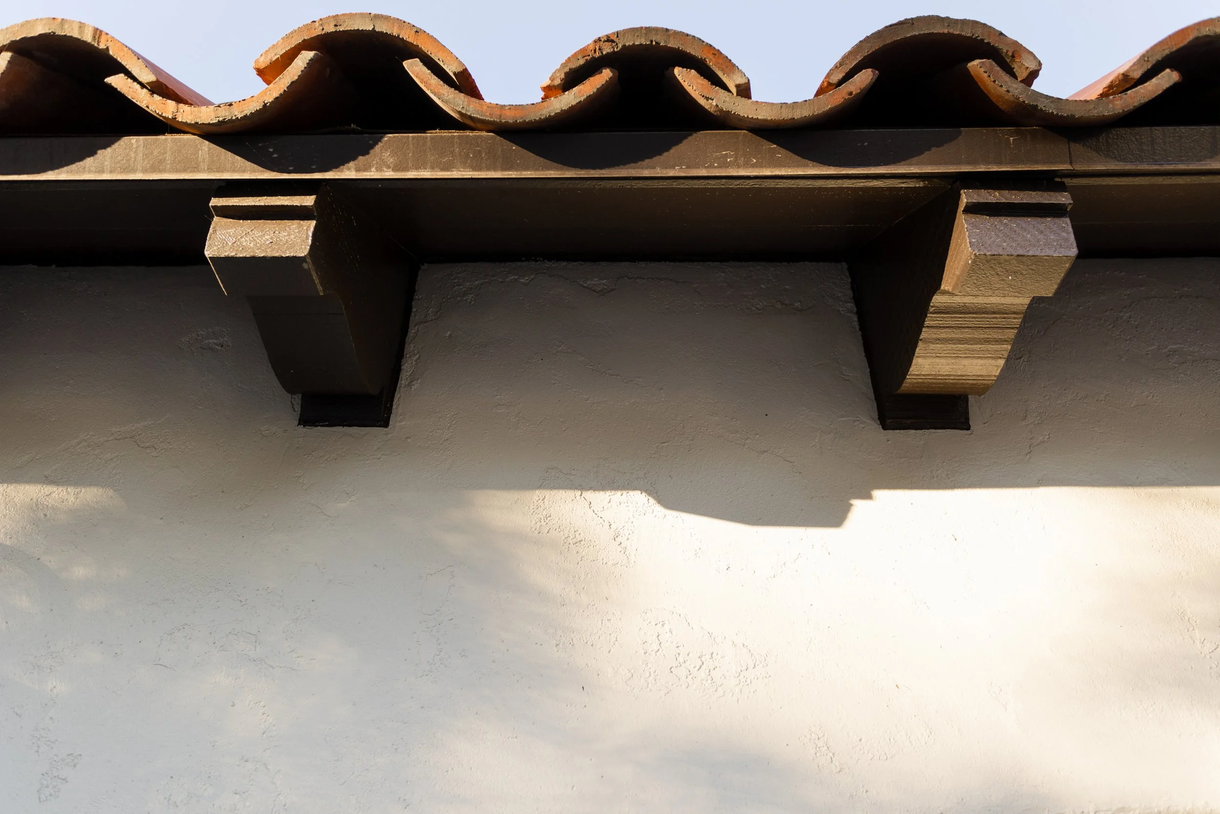 Curved red roof tiles and dark wood eave detail
