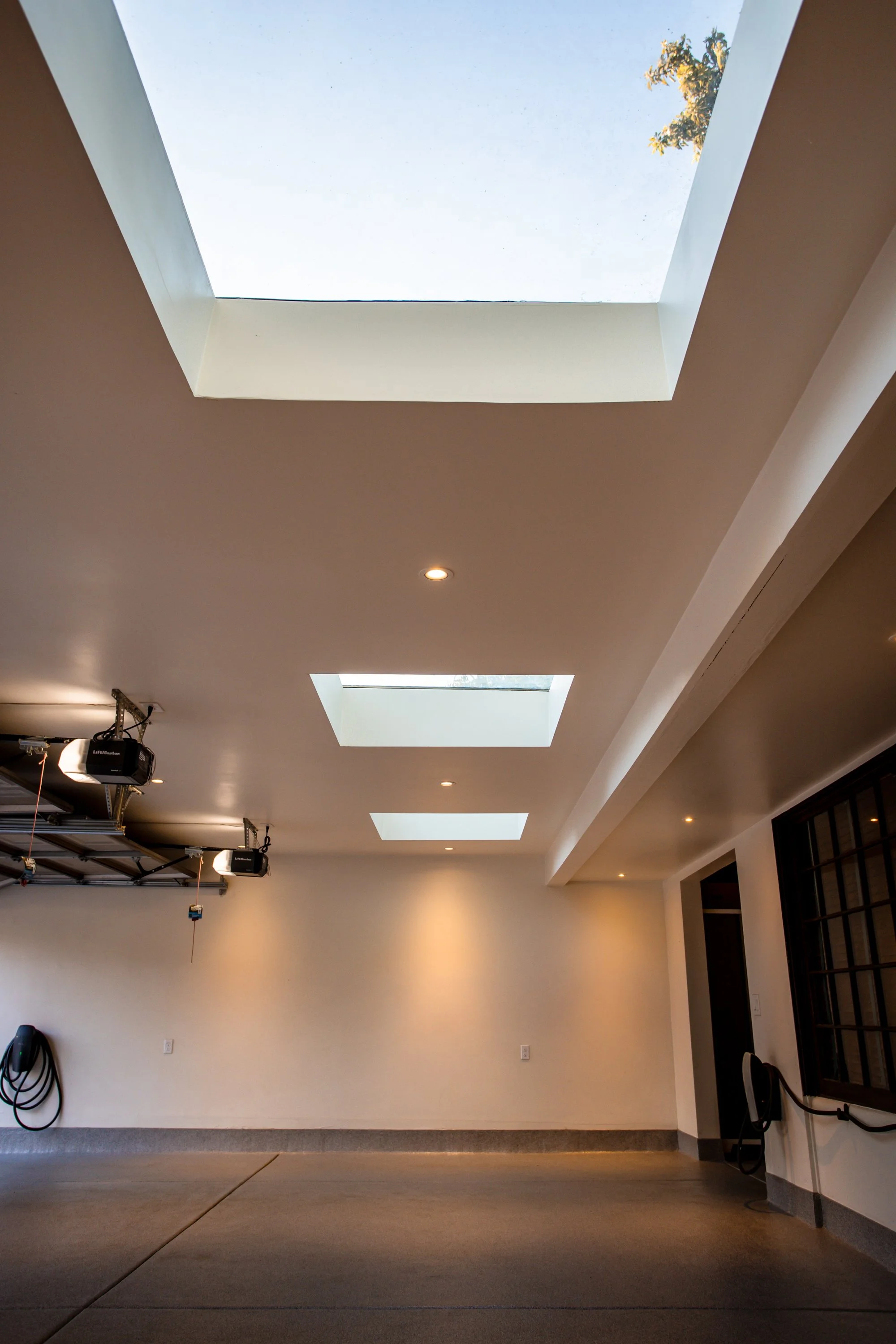 Bright three-car garage interior with skylights and ceiling-mounted storage