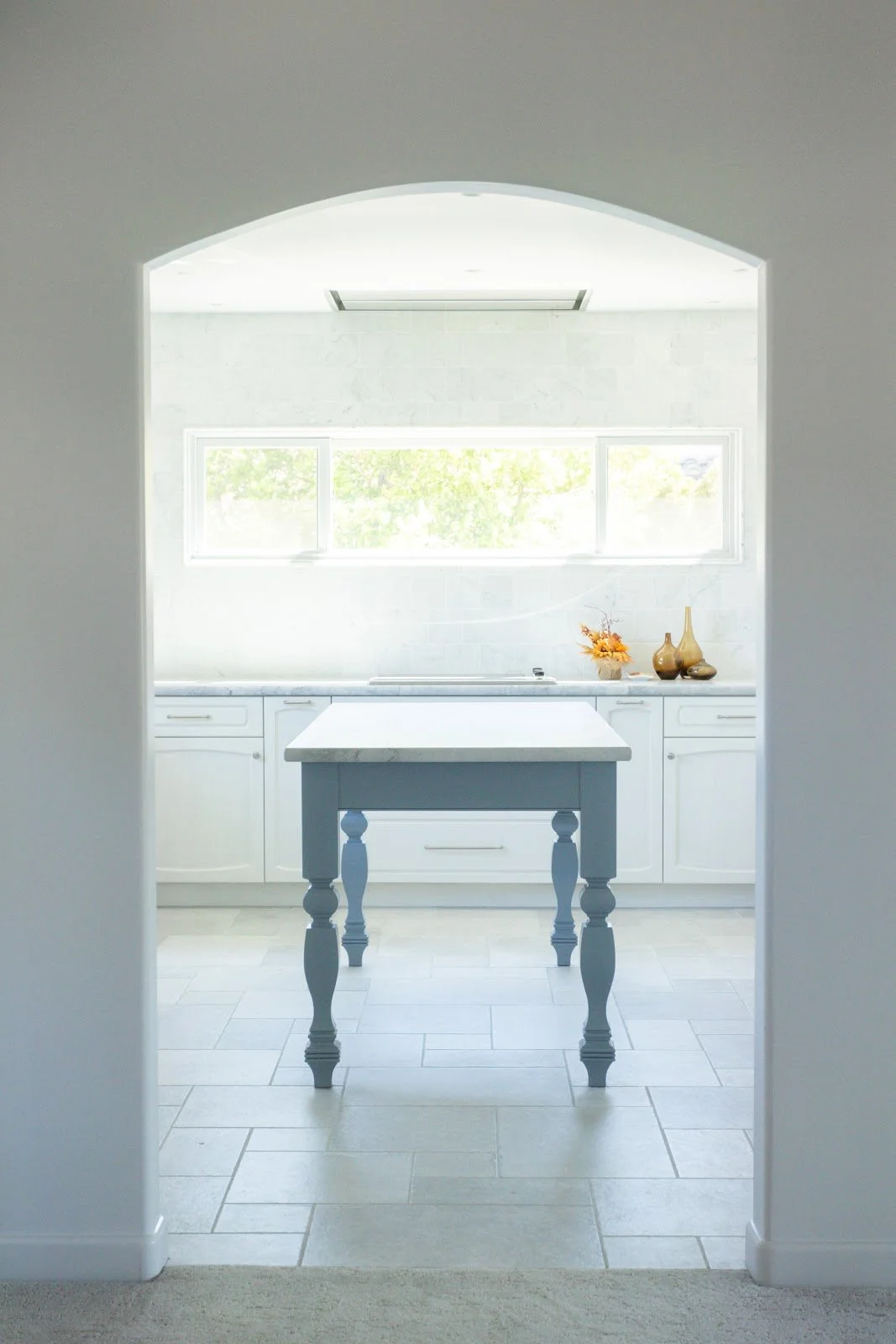 Bright white kitchen with marble island and farmhouse sink