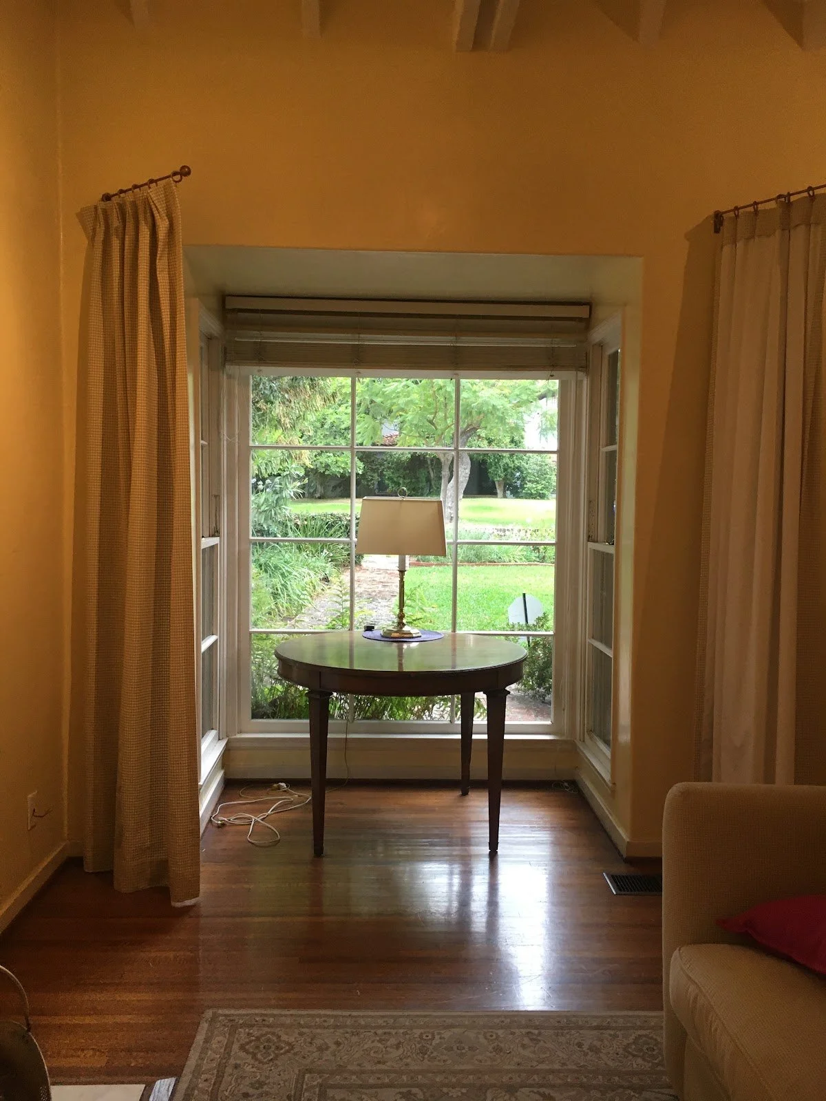 Bay window with a small table in the living room before renovation