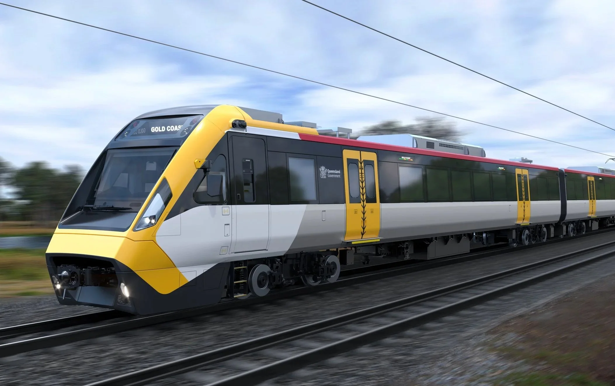 Modern train with yellow, black, red and white colors traveling on a track with blue sky and some clouds in the background.